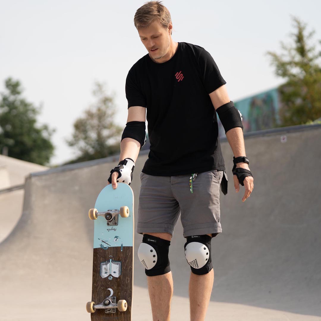 Junger Vater in Skateschutzausrüstung in einem Skatepark